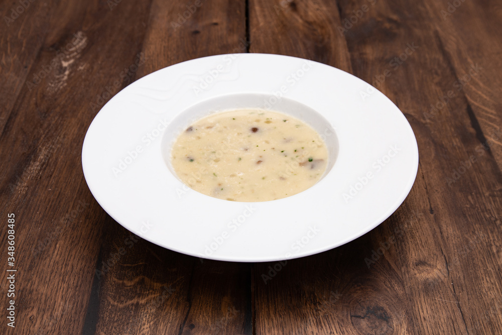 Cream soup with mushrooms and on wooden table. A plate of Mushroom Cream-soup. Cream soup with mushrooms and on wooden table. A plate of Mushroom Cream-soup.