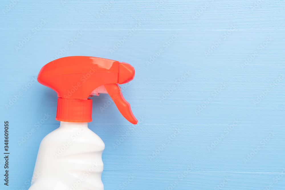 Bottle of cleaning spray with a white case without inscriptions and a red bright dispenser on a wooden light blue background Bottle of cleaning spray with a white case without inscriptions and a red bright dispenser on a wooden light blue background