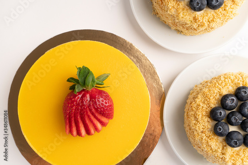 Layer mango cake with strawberries and muffins with blueberries