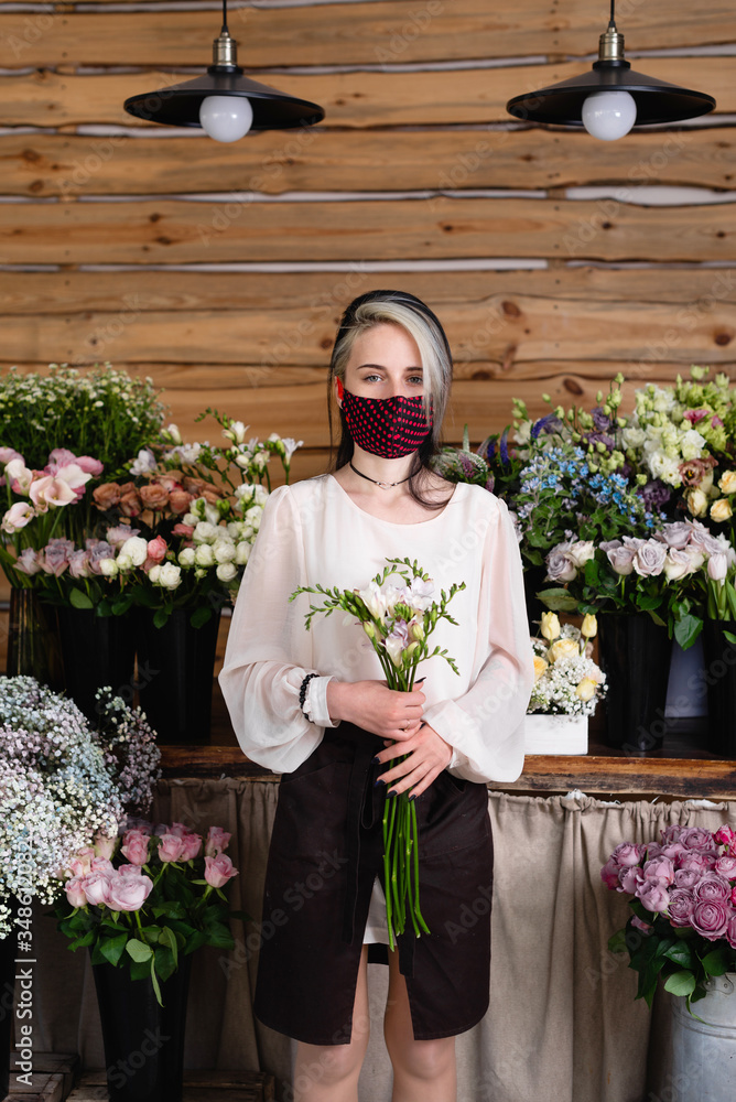 Fototapeta premium small business work concept during pandemic and quarantine. Young woman small business representative wearing a medical protective mask.