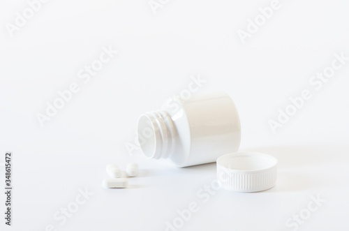 White pills and plastic bottle on a white background.