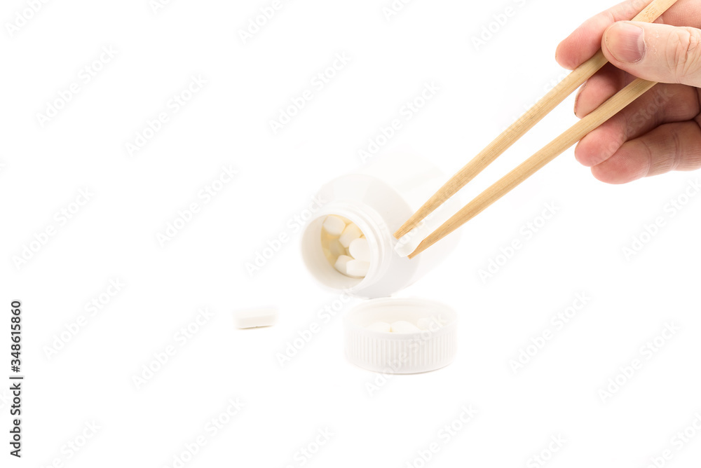Man's hand holds chopsticks with a medical tablet. Man's hand holds chopsticks with a medical tablet.