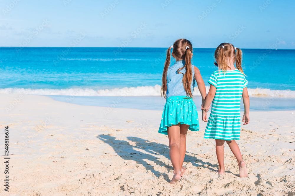 Little happy funny girls have a lot of fun at tropical beach playing together.