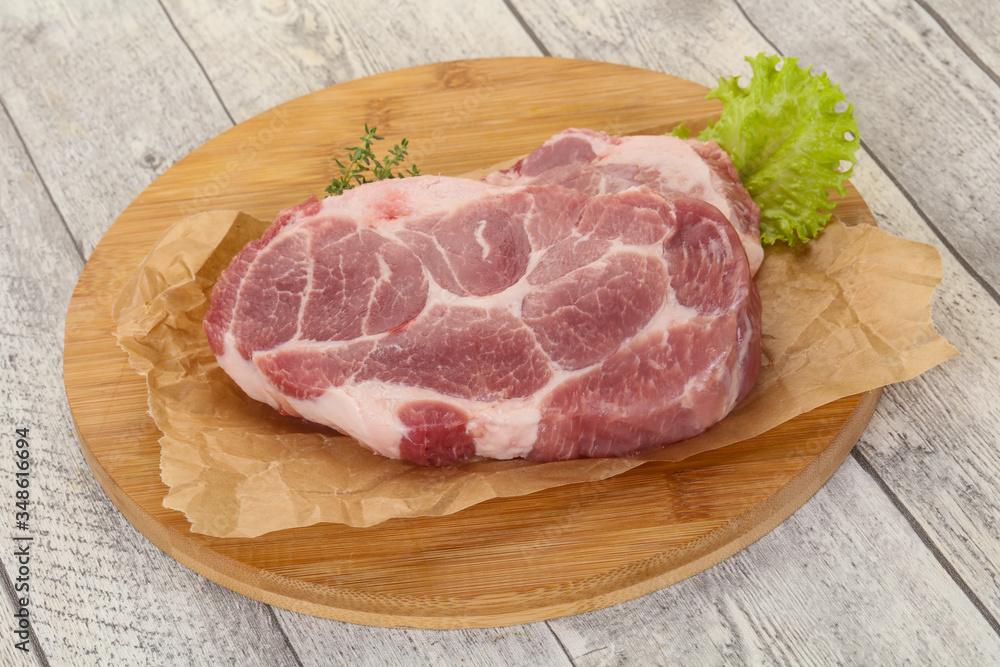 Raw pork steak over wooden board