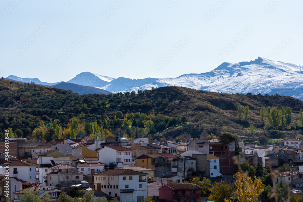 View of the Andalusian town of Beas de Granada with the snow-capped peaks of Sierra Nevada in the background