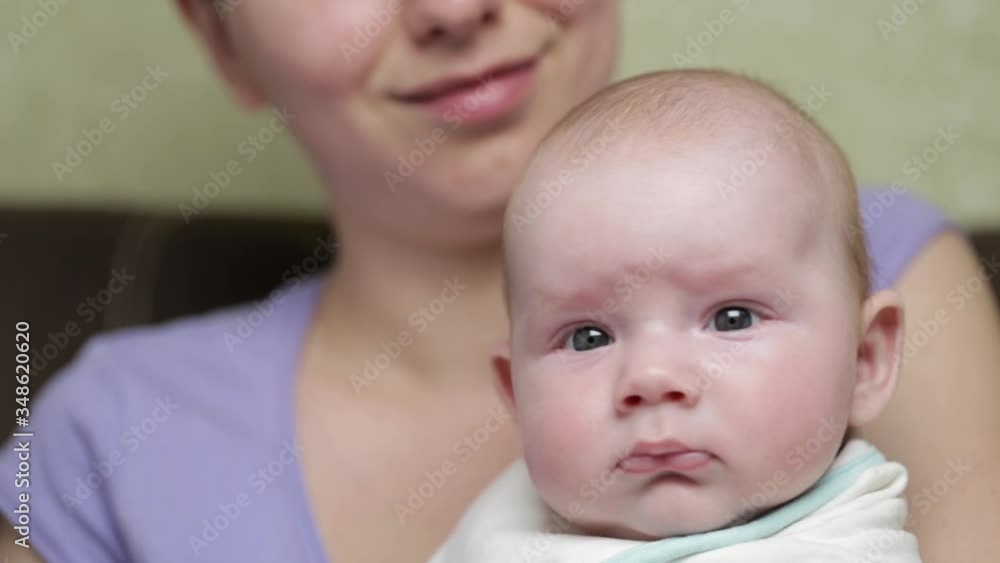 Happy Infant. Emotions closeup. Portrait of charming smiling toddler with chubby cheeks in his mother's arms. Mother holding her new born baby boy. Happy Mom and child. Happy Infant. Emotions closeup. Portrait of charming smiling toddler with chubby cheeks in his mother's arms. Mother holding her new born baby boy. Happy Mom and child.