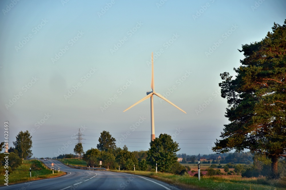 Road with view to wind turbines installations for green energy in the countryside
