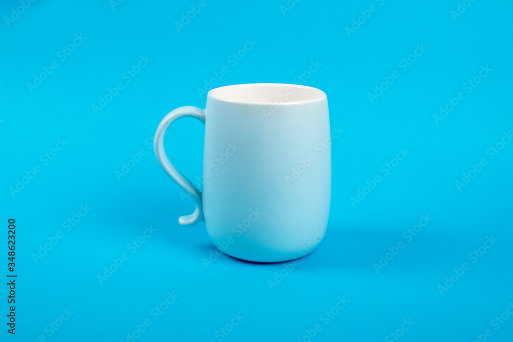 Obraz premium Glass cup isolated on a blue background. Dishes for drinks. Food concept.