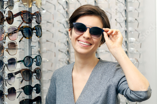 Beautiful woman chooses on sunglasses in an optics store