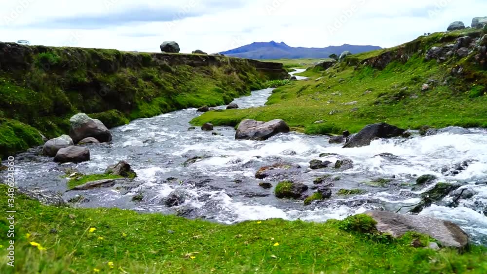 Fast running water in a stream with rocks and grassy banks Fast running water in a stream with rocks and grassy banks