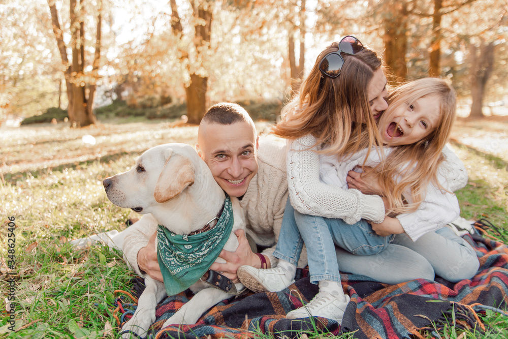 Happy beautiful family with dog labrador is having fun are sitting on green grass in park. Happy beautiful family with dog labrador is having fun are sitting on green grass in park.