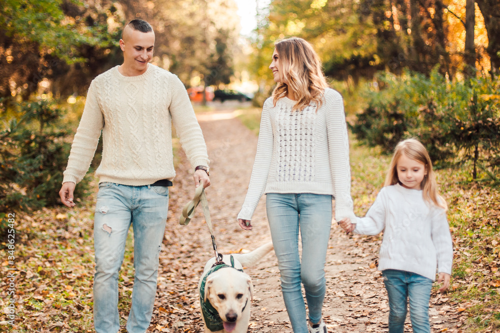 Obraz premium Happy family is having fun with dog labrador outdoors.