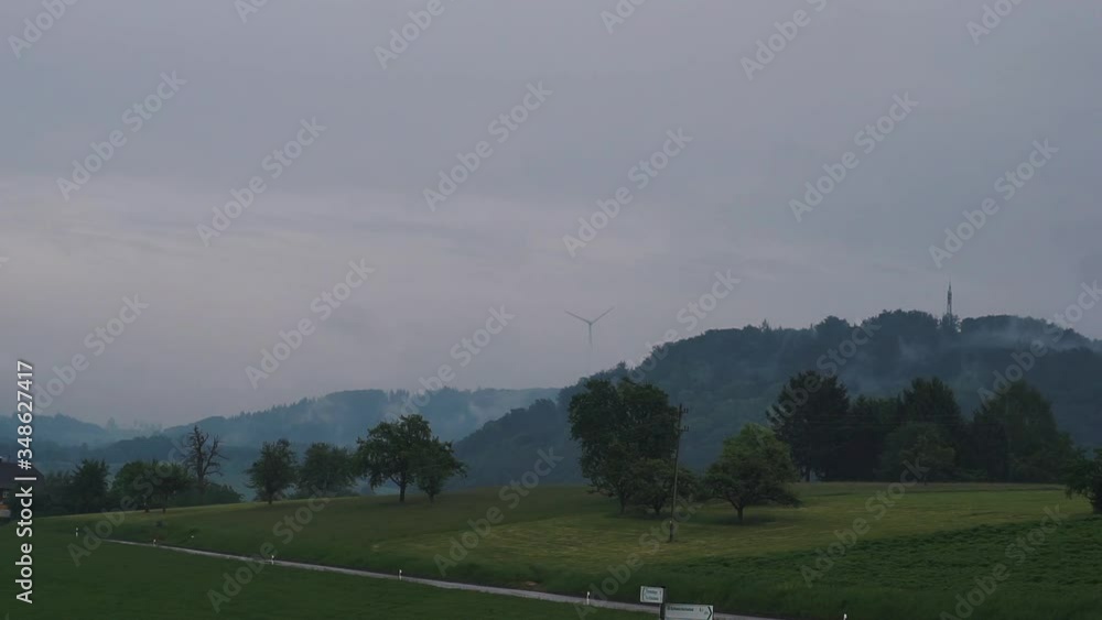 Windrad verschwindet in der Ferne im Nebel an einem verregneten Tag und ein Bus fährt vorbei Windrad verschwindet in der Ferne im Nebel an einem verregneten Tag und ein Bus fährt vorbei