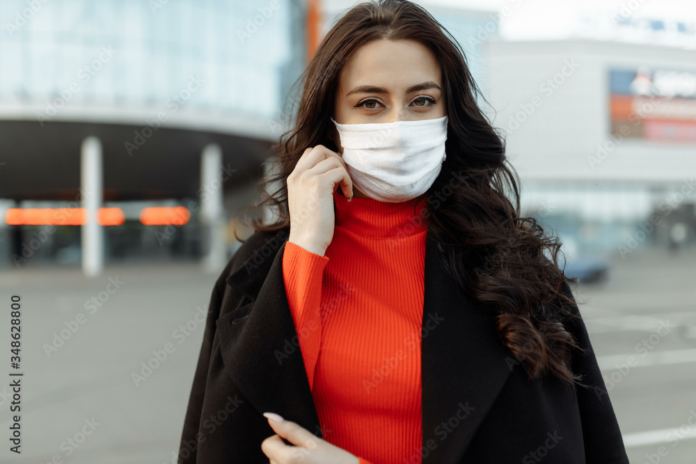 Portrait of beautiful woman walking on the street wearing protective mask as protection against infectious diseases. Attractive unhappy model with flu outdoors Portrait of beautiful woman walking on the street wearing protective mask as protection against infectious diseases. Attractive unhappy model with flu outdoors