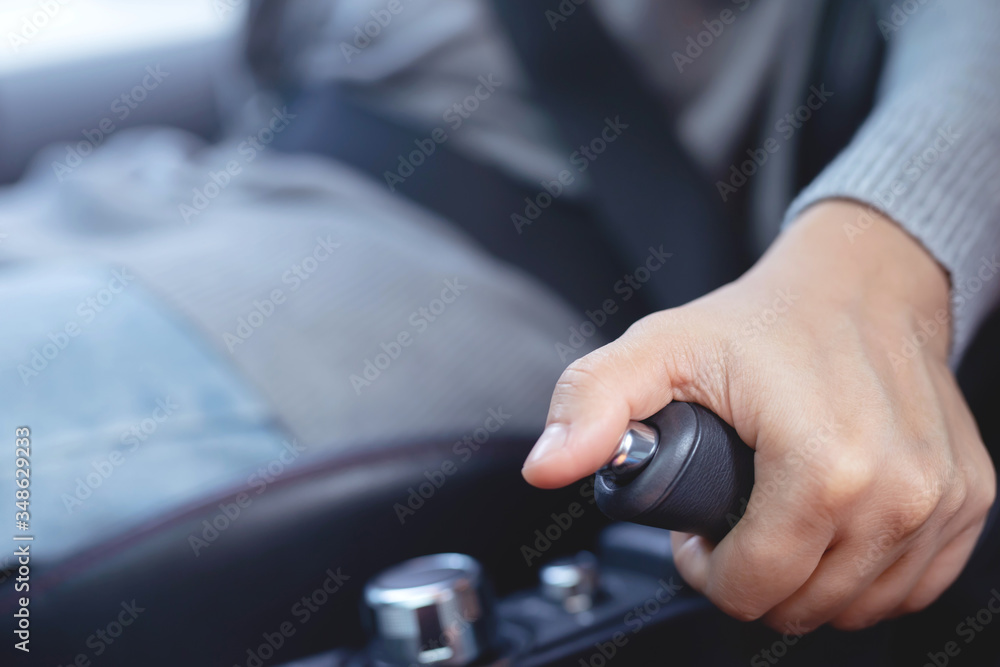 Closeup of person pulling hand brake lever in car For safety while parking. concept lock or unlock to protect against safety transport travel. Closeup of person pulling hand brake lever in car For safety while parking. concept lock or unlock to protect against safety transport travel.