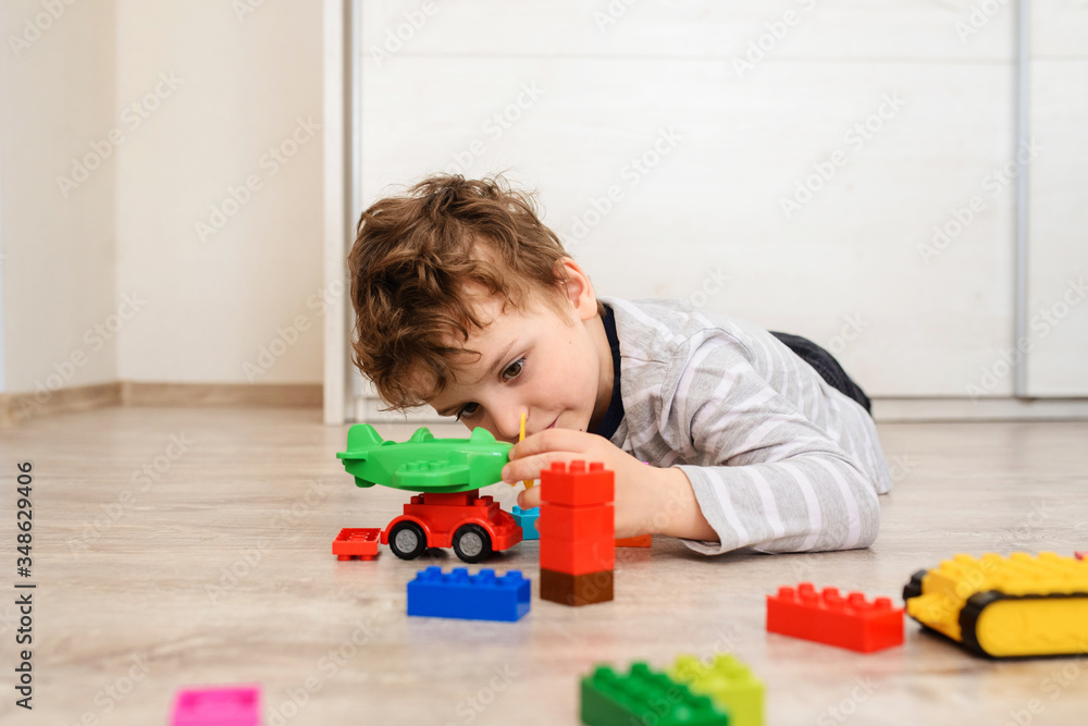 Happy little boy kid is lying on the wood floor and playing Happy little boy kid is lying on the wood floor and playing