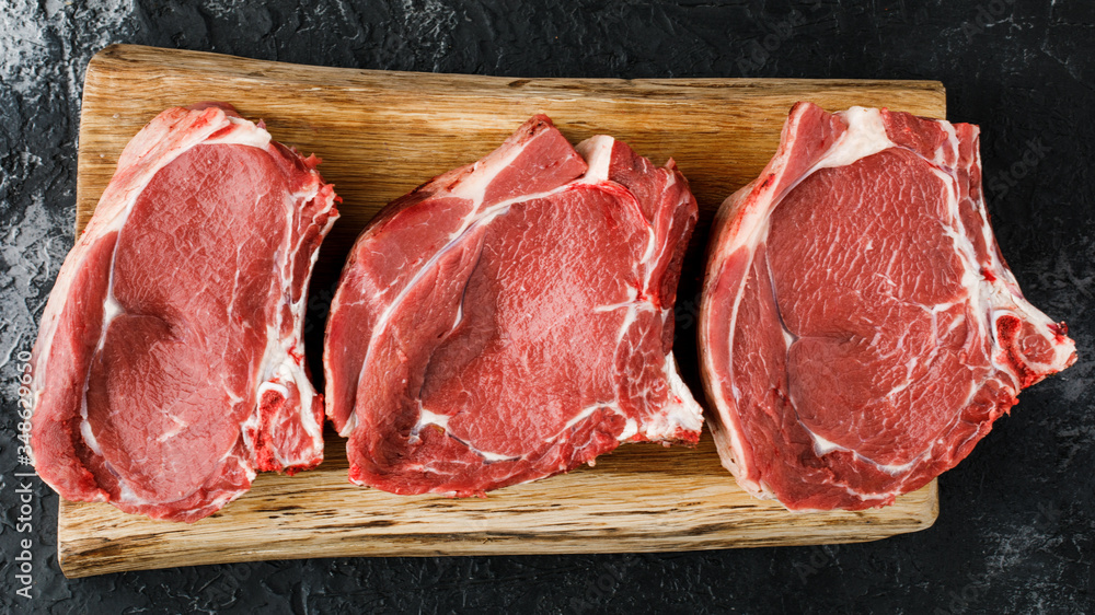 Raw fresh meat, beef steak on a black background, top view.