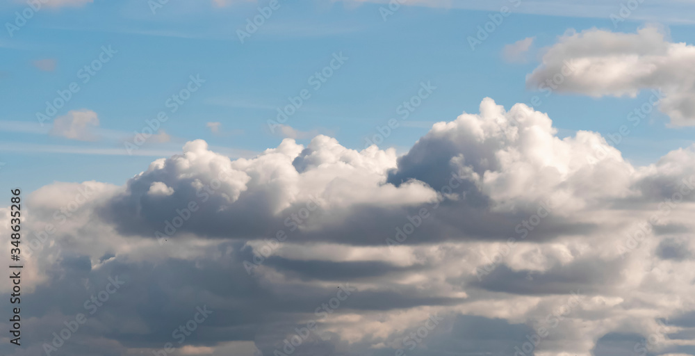 Lush, voluminous, white clouds in a clear blue sky with dark clouds, illuminated by the rays of the sun on a Sunny day. Unique cumulus. Landscape of sky and earthly atmosphere. Lush, voluminous, white clouds in a clear blue sky with dark clouds, illuminated by the rays of the sun on a Sunny day. Unique cumulus. Landscape of sky and earthly atmosphere.