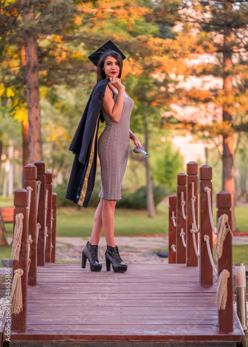 Woman taking a lot of different graduation photos in a beautiful botanical park.