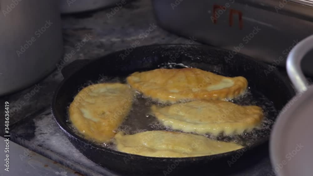 chef cooks ruddy flat patties with meat in boiling oil chef cooks ruddy flat patties with meat in boiling oil