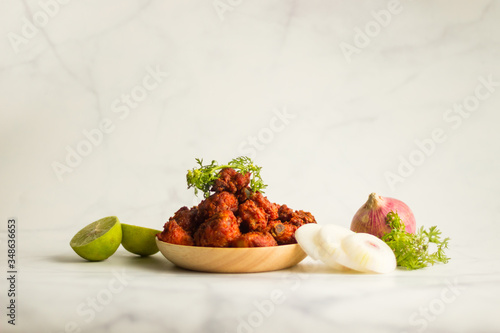 Fried chicken served with raw onion and lemon with coriander for garnishing 