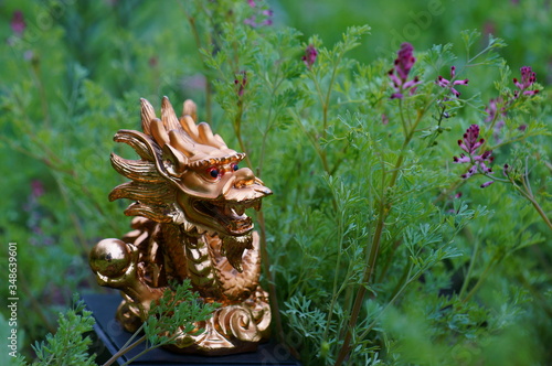 Dragon statuette in the green garden. Symbol of harmony and greatness.