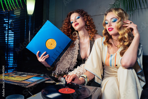 Photography Two pretty girls models listening to vinyl records on the oldschool turntable