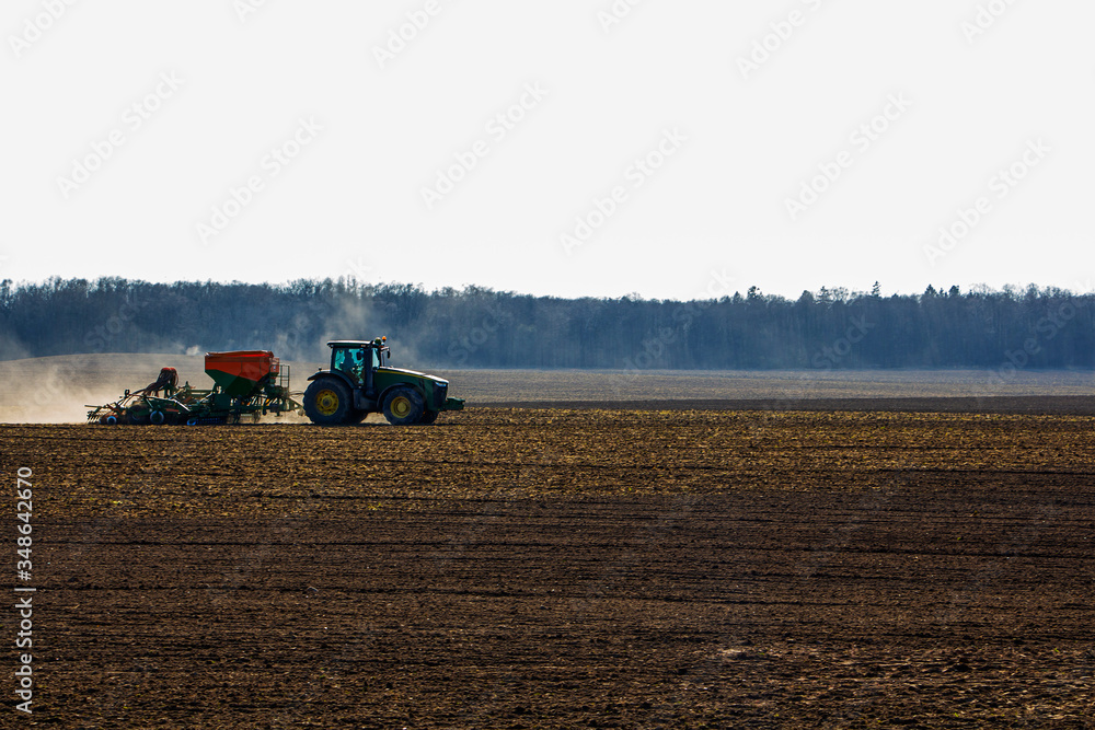 Fototapeta premium a large tractor with a seeder goes through the field.