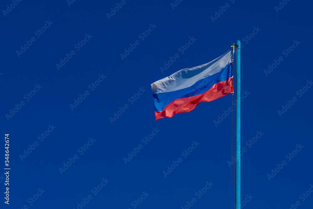 The flag of Russia is developing against a clear blue sky The flag of Russia is developing against a clear blue sky