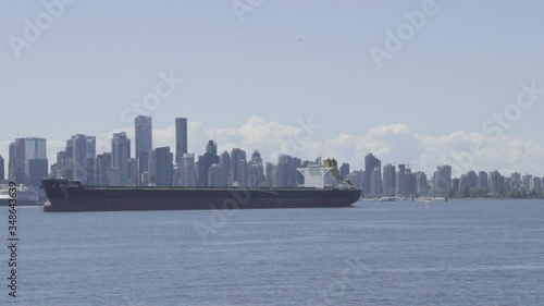 4K video of boat tanker container ship sailing in downtown of a large city with large buildings skyscrapers in calm water day empty waiting to transport cargo over the ocean sea cargo ship