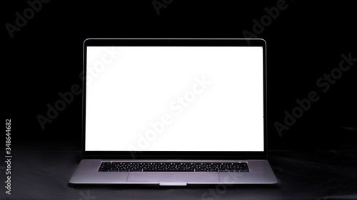Computer with blank screen on the table on a black background. Mockup and space for text and advertising. Copy space
