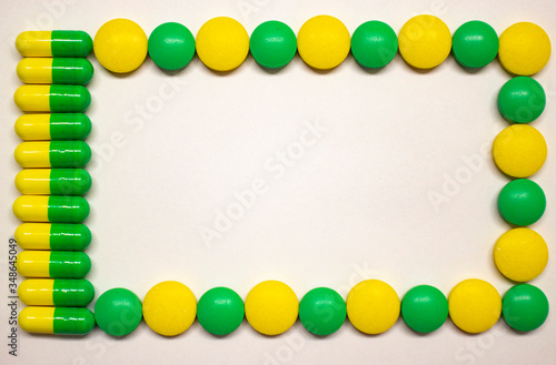 Yellow-green capsules and pills in the form of a frame for inscriptions on a blue background. The concept of the pharmaceutical industry. Pharmacy. Disease Prevention