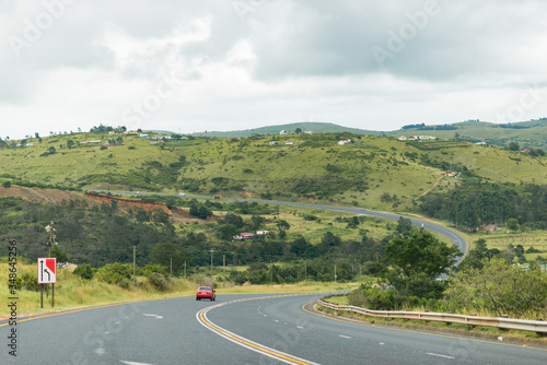 Südafrika, KwaZulu-Natal, East Griqualand, Straße inmitten einer begrünten Hügellandschaft, auf dem Land in KwaZulu-Natal an der Grenze zu Eastern Cape