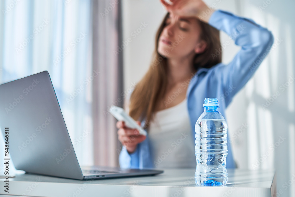Upset tired working woman suffering from heat and hot weather during online work at computer at warm summer day Upset tired working woman suffering from heat and hot weather during online work at computer at warm summer day