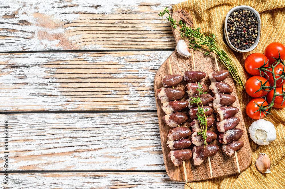 Raw shish kebab with chicken hearts on a wooden skewer. White background. Top view. Copy space