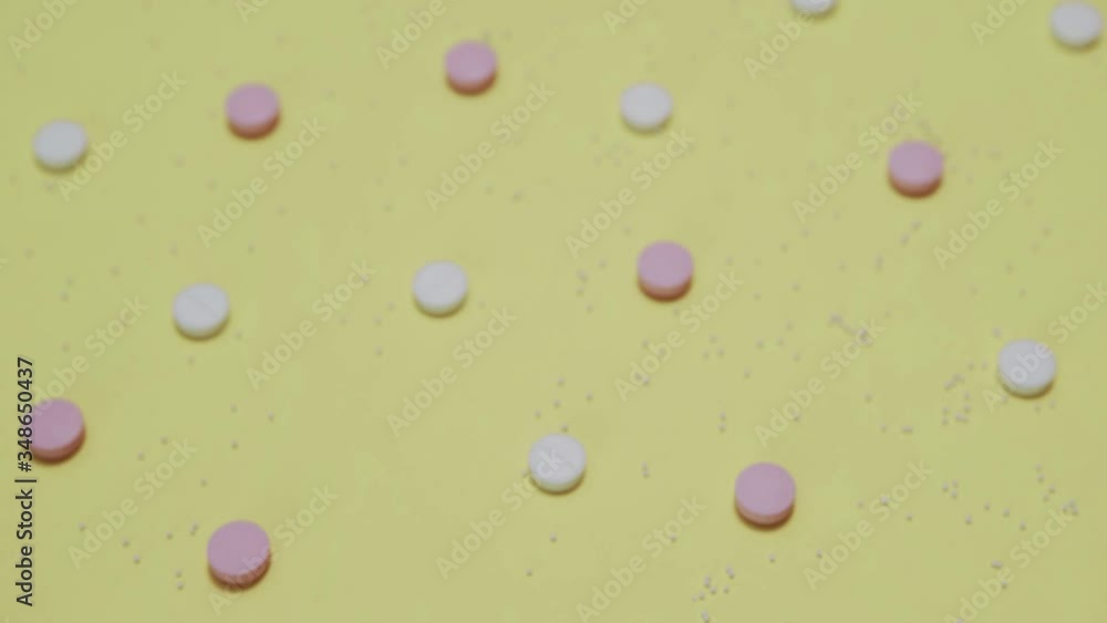 Pink and white pills on yellow background Pink and white pills on yellow background