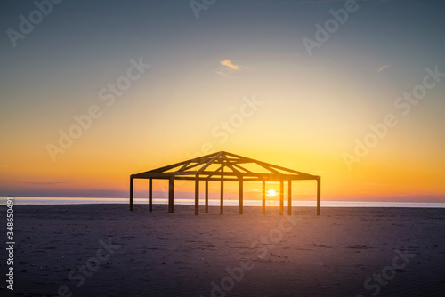 Silhouette Built Structure By Sea Against Orange Sky