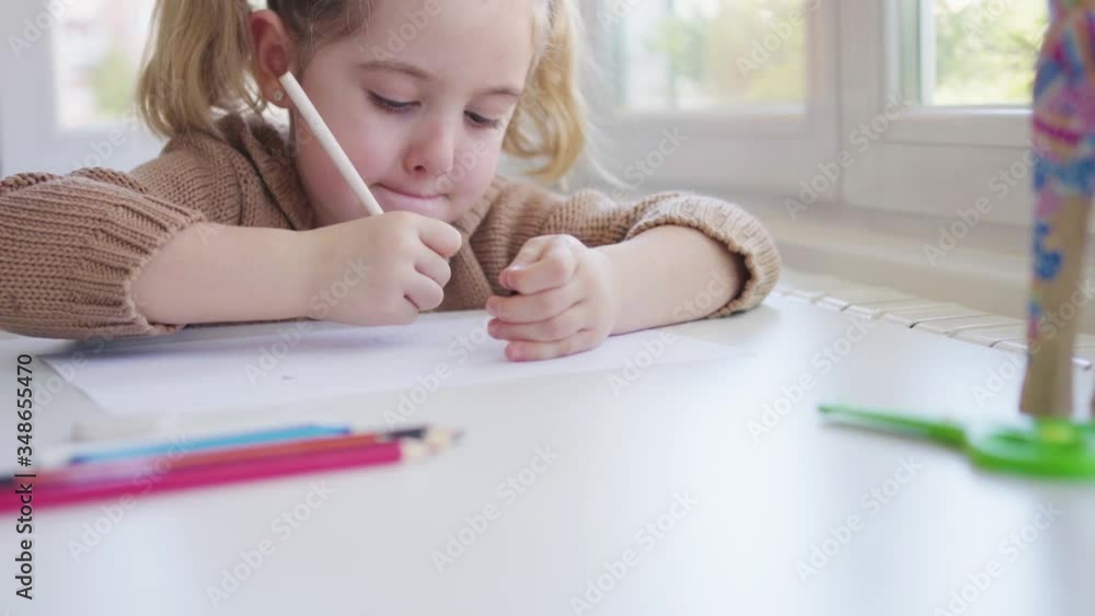 Child with paper and pencil sitting on chair Child with paper and pencil sitting on chair