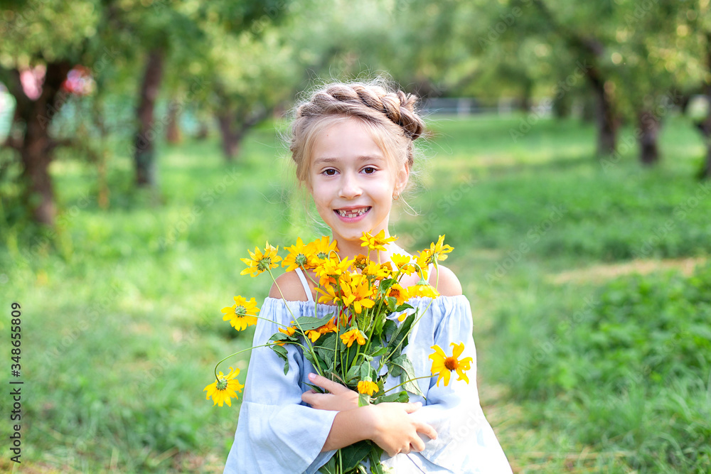 Cute little smiling girl in with a bouquet of yellow flowers in garden. Cheerful child with daisies. Portrait little girl with bouquet of chamomiles in sunny summer day. Gardening. Childhood concept.