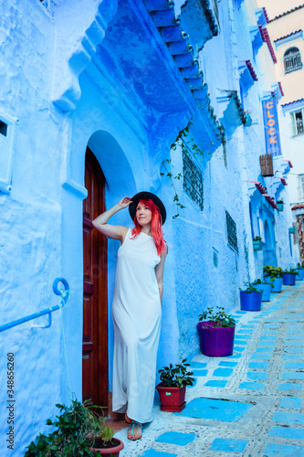 Beautiful caucasian woman in a white dress and a boater hat posing in a blue city in Morocco. Chefchaouen. © viktoriia1974