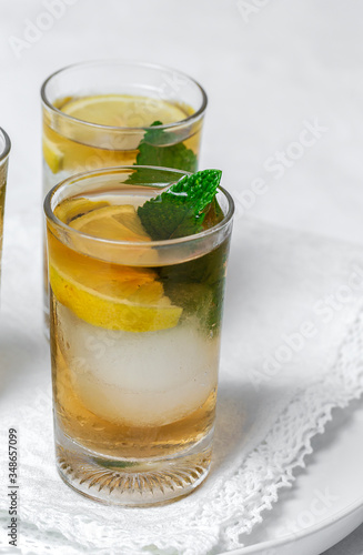 tea with ice, mint and lemon wedges on white table