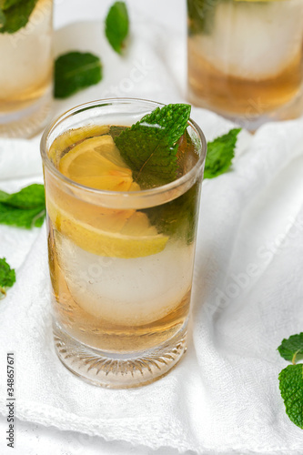 tea with ice, mint and lemon wedges on white table