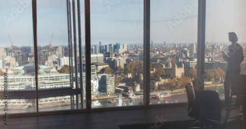 Silhouette businessman at highrise window overlooking city, London, UK photo