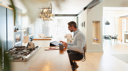Businessman at digital tablet working from home in modern kitchen