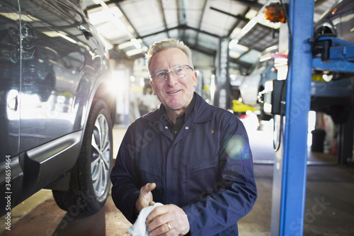 Portrait confident male mechanic wiping hands in auto repair shop photo