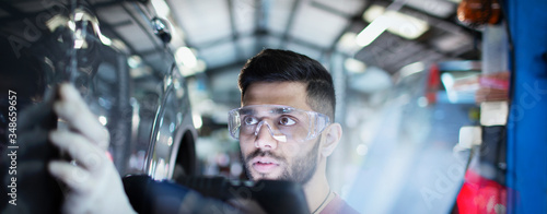 Focused male mechanic examining car in auto repair shop