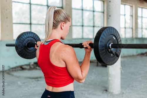 Fit blond woman weight lifting in red sportswear. Training, active lifestyle.