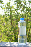 Bottle of water on a background of greenery