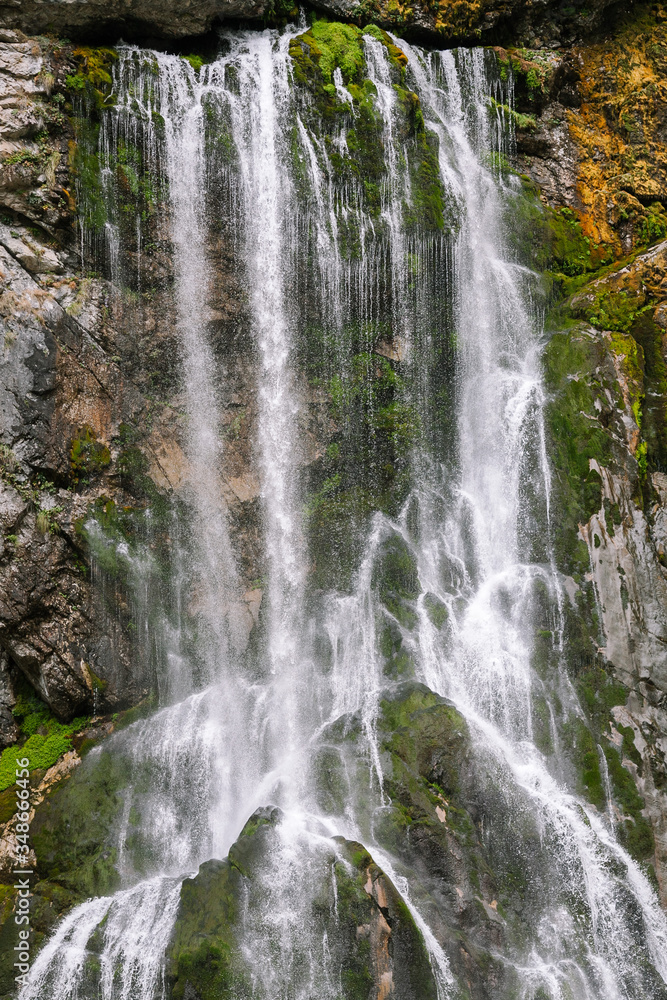A mountain waterfall. A strong stream of water dropping down among rocks A mountain waterfall. A strong stream of water dropping down among rocks