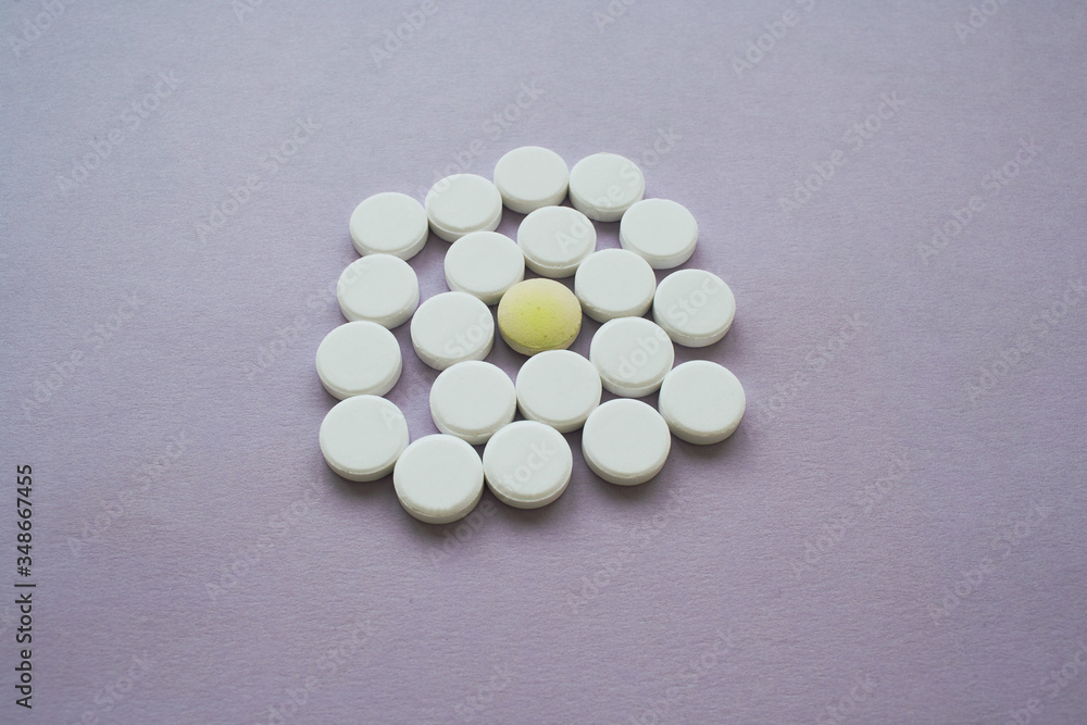 Round white pills and yellow one on a purple background in the middle of shot, isolated Round white pills and yellow one on a purple background in the middle of shot, isolated